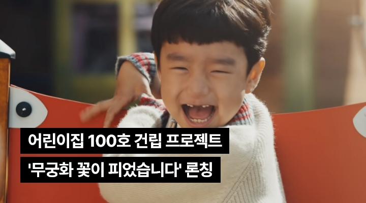한 어린아이가 즐겁게 미소 짓고 있는 이미지와 어린이집 100호 건립 프로젝트 ‘무궁화 꽃이 피었습니다’ 론칭 텍스트